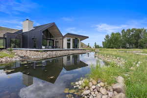 Rear view of property featuring a patio, a chimney, and a water view