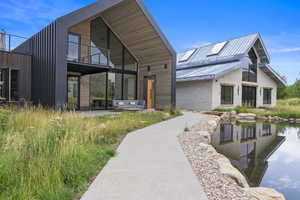 Rear view of property featuring stone siding, a patio area, and a balcony