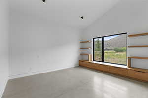 Empty room with concrete floors, a mountain view, and high vaulted ceiling