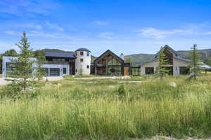 Back of house featuring stone siding, a mountain view, and a chimney