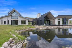 Rear view of property featuring a patio area, a chimney, and stone siding