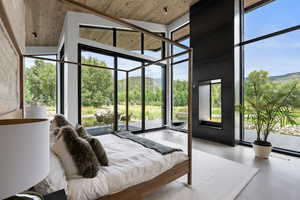 Bedroom featuring access to outside, floor to ceiling windows, a mountain view, concrete flooring, and a high ceiling
