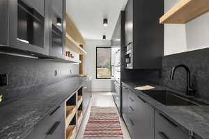 Kitchen with open shelves, dark cabinetry, backsplash, appliances with stainless steel finishes, and glass insert cabinets