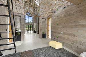Hall featuring a high ceiling, concrete floors, wood walls, and a wall of windows