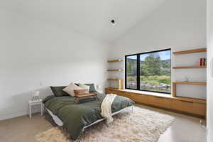 Bedroom with high vaulted ceiling, finished concrete floors, and a mountain view