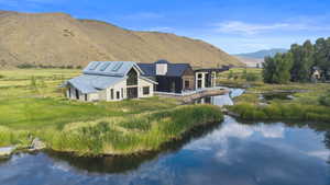 Back of property with a metal roof and a water and mountain view