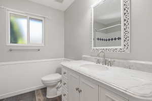 Full bathroom featuring wood finished floors, vanity, a wainscoted wall, and a shower