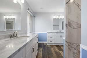 Bathroom with two vanities, wood finished floors, and wainscoting