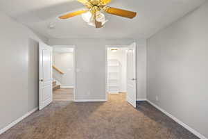Unfurnished bedroom featuring a spacious closet, carpet floors, and a ceiling fan