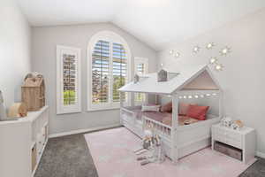 Carpeted bedroom with vaulted ceiling and baseboards