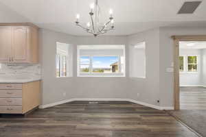 Unfurnished dining area with a chandelier and dark wood finished floors