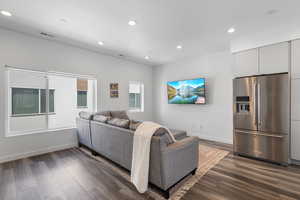 Living area with dark wood-type flooring and recessed lighting