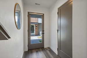 Doorway to outside with dark wood-type flooring and baseboards
