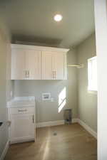 Laundry room with washer hookup, cabinet space, light wood finished floors, and recessed lighting