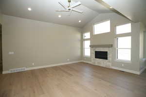 Great room featuring a stone fireplace, high vaulted ceiling, light wood-style flooring, ceiling fan, and recessed lighting