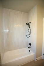 Full bath with wood finished floors and washtub / shower combination