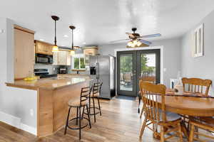 Kitchen with stainless steel fridge, a peninsula, electric range oven, light wood finished floors
