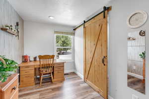 Primary bedroom office featuring a barn door and wood finished floors