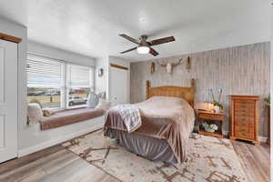 Bedroom featuring wood walls, wood finished floors, a textured ceiling, ceiling fan, and a closet