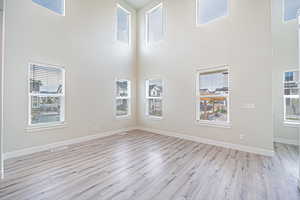 Unfurnished room with light wood finished floors and a towering ceiling