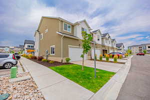 View of side of home featuring a residential view, a garage, driveway, and stucco siding