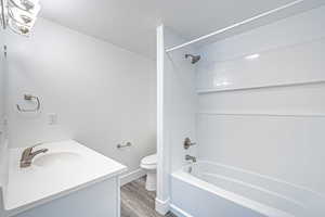 Full bathroom with wood finished floors, bathing tub / shower combination, vanity, and a textured ceiling