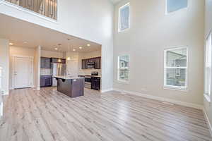 Kitchen with open floor plan, light countertops, stainless steel appliances, light wood finished floors, and dark brown cabinetry