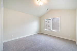 Empty room with lofted ceiling and carpet floors