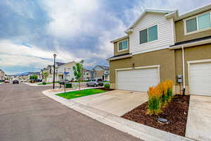 View of side of property featuring a residential view, stucco siding, concrete driveway, and an attached garage