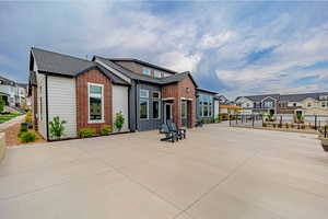 Back of house with a patio, a residential view, roof with shingles, and brick siding