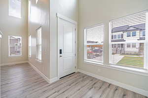 Foyer entrance with light wood-style floors and a towering ceiling