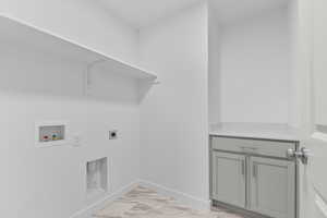 Washroom featuring hookup for an electric dryer, hookup for a washing machine, cabinet space, and light marble finish floors
