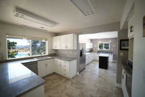 Kitchen featuring appliances with stainless steel finishes, white cabinetry, hanging light fixtures, and light countertops