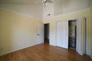 Unfurnished bedroom featuring wood finished floors, a towering ceiling, a closet, and a ceiling fan