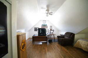 Office featuring a textured ceiling, wood finished floors, a ceiling fan, and vaulted ceiling