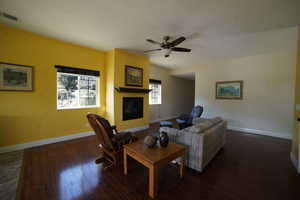 Living area featuring a fireplace, wood finished floors, a ceiling fan, and a textured ceiling