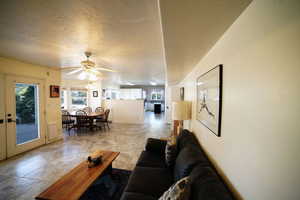 Living area featuring ceiling fan and a textured ceiling