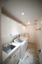 Laundry area featuring cabinet space, washer and dryer, and recessed lighting