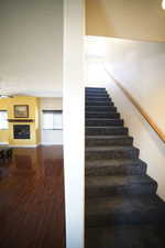 Staircase featuring wood finished floors, a fireplace, and ceiling fan