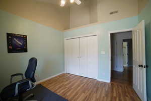 Unfurnished office featuring wood finished floors, ceiling fan, and a high ceiling