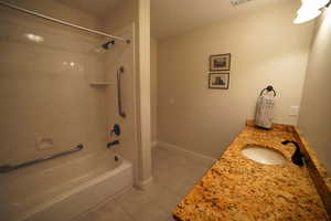 Full bathroom featuring tile patterned floors, tub / shower combination, vanity, and a textured ceiling