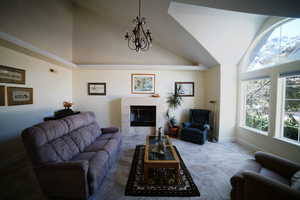 Living room featuring a tile fireplace, high vaulted ceiling, and a chandelier