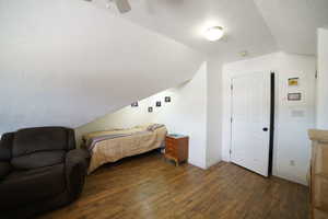 Bedroom with lofted ceiling, wood finished floors, a textured ceiling, and a ceiling fan