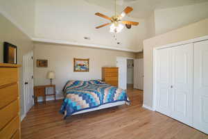 Bedroom featuring a high ceiling, light wood-style floors, a closet, and ceiling fan