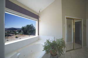 Full bath featuring a mountain view, a tub with jets, tile patterned flooring, and lofted ceiling