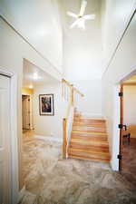 Stairs with a towering ceiling and a ceiling fan