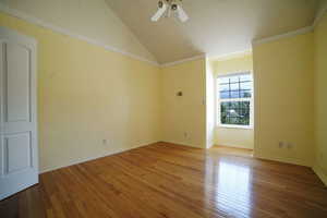 Spare room featuring hardwood / wood-style floors, a ceiling fan, and vaulted ceiling