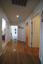 Hallway with an upstairs landing, wood finished floors, and recessed lighting