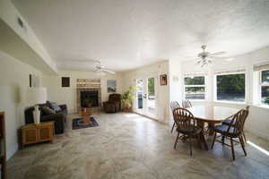 Dining room with a ceiling fan, a brick fireplace, french doors, a textured ceiling, and radiator