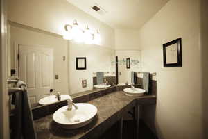 Bathroom featuring double vanity and a textured ceiling